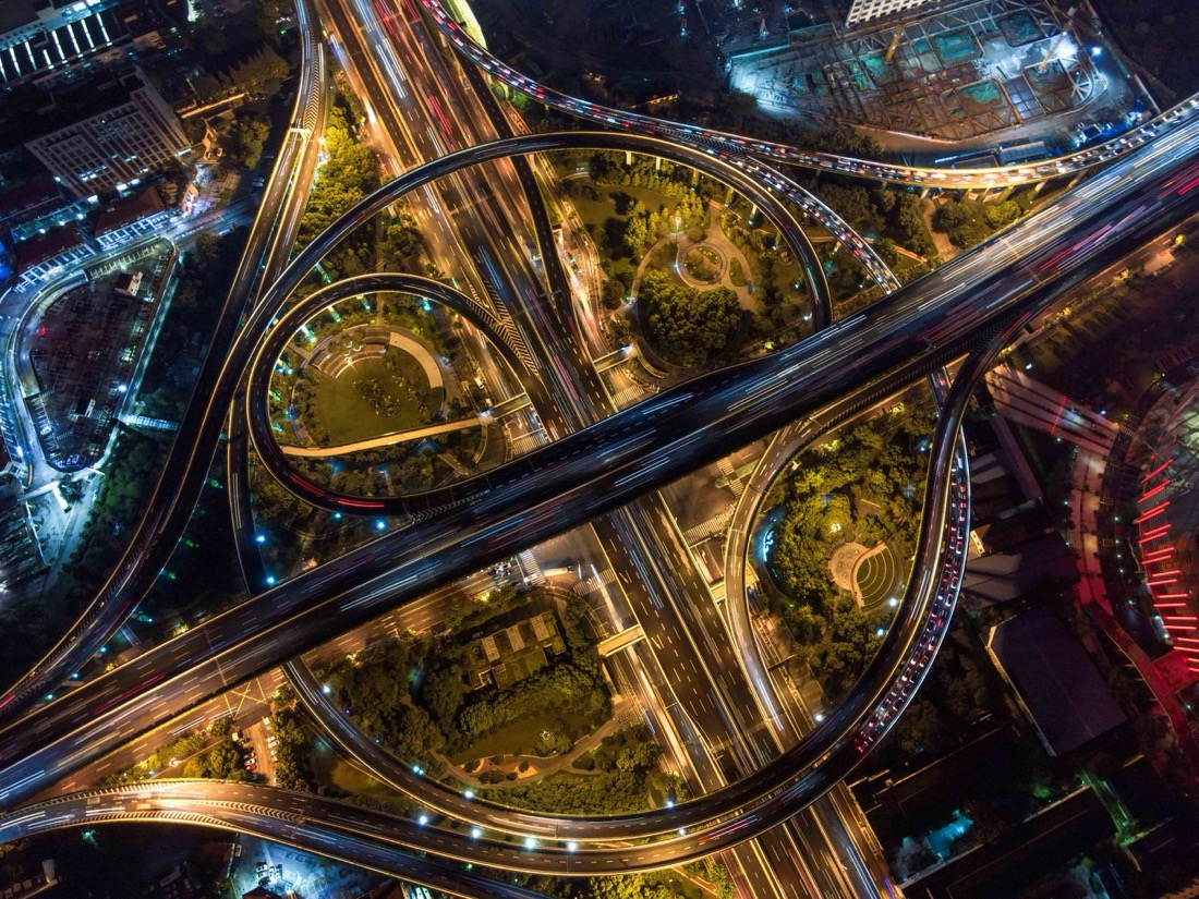 Aerial view of a highway interchange at night with flowing light trails
