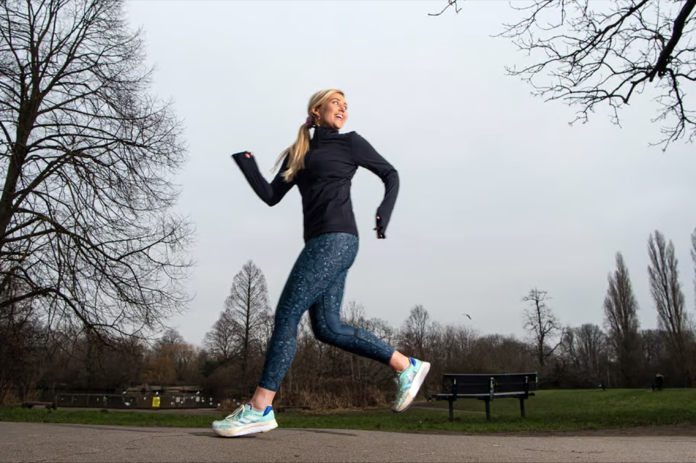 A runner in a park running backwards, landing on her toes
