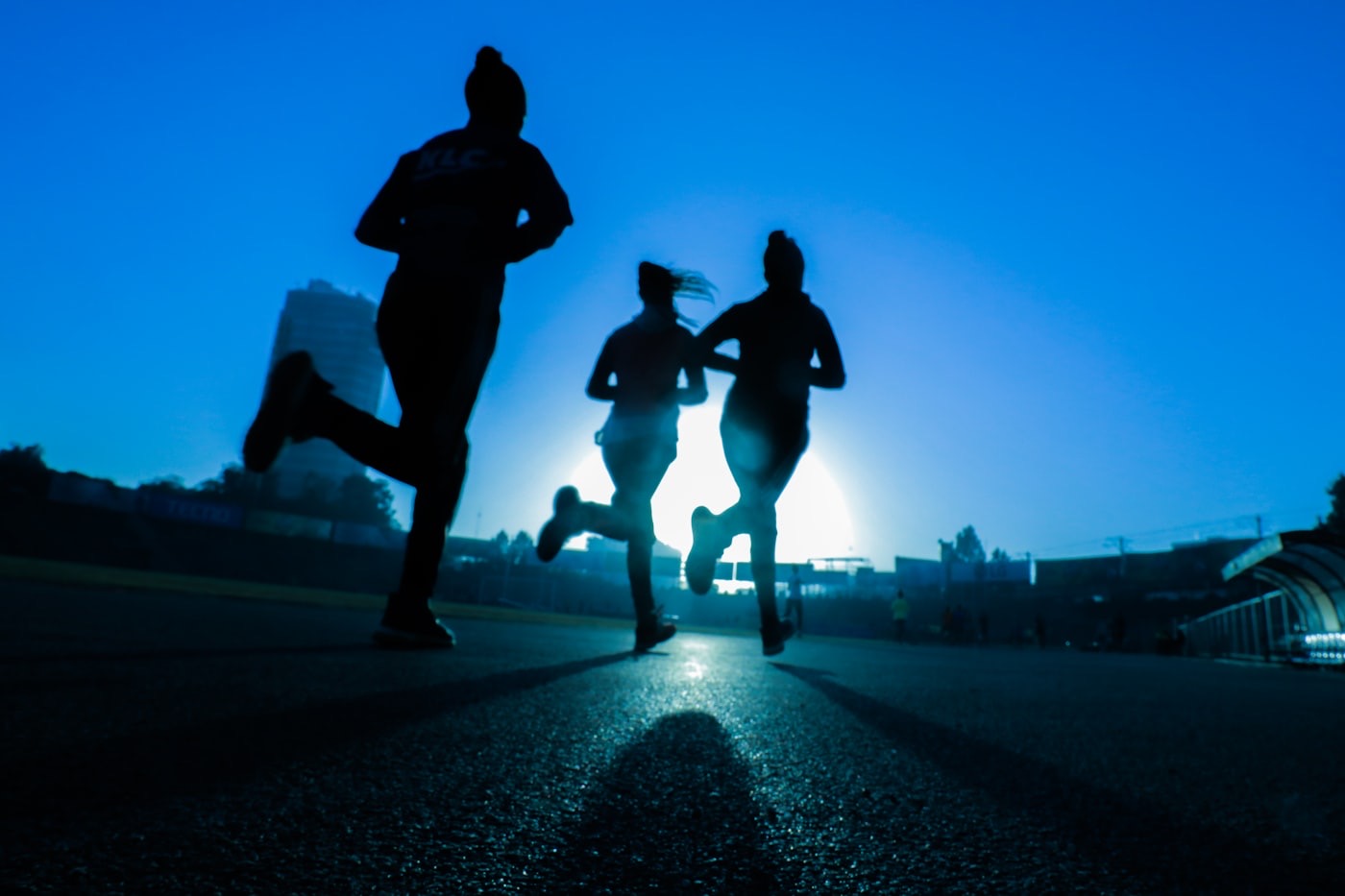 Runners with knees up high, silhouetted against the morning sun